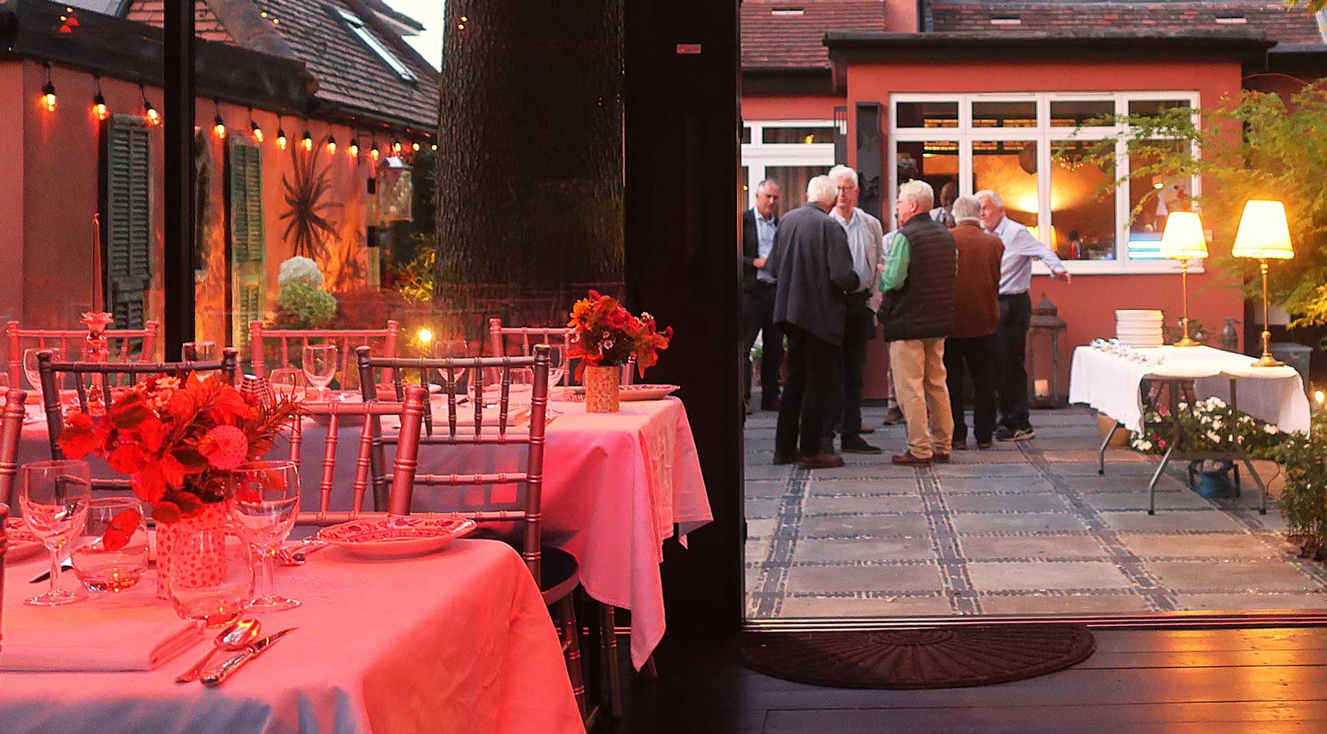 Rosy's kitchen set up for fine dining at night, with a beautiful red glow. Guests in the background having fun.