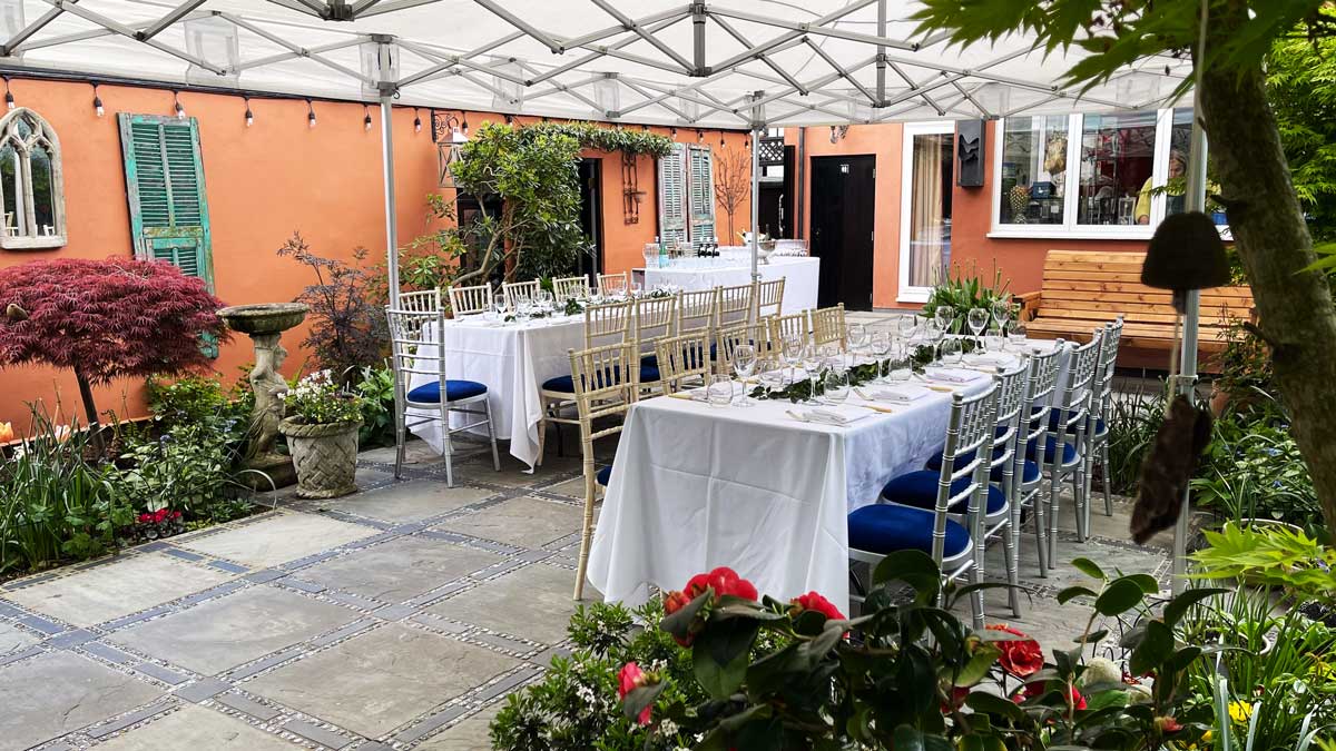 Marquee in the patio, with two set tables underneath it.